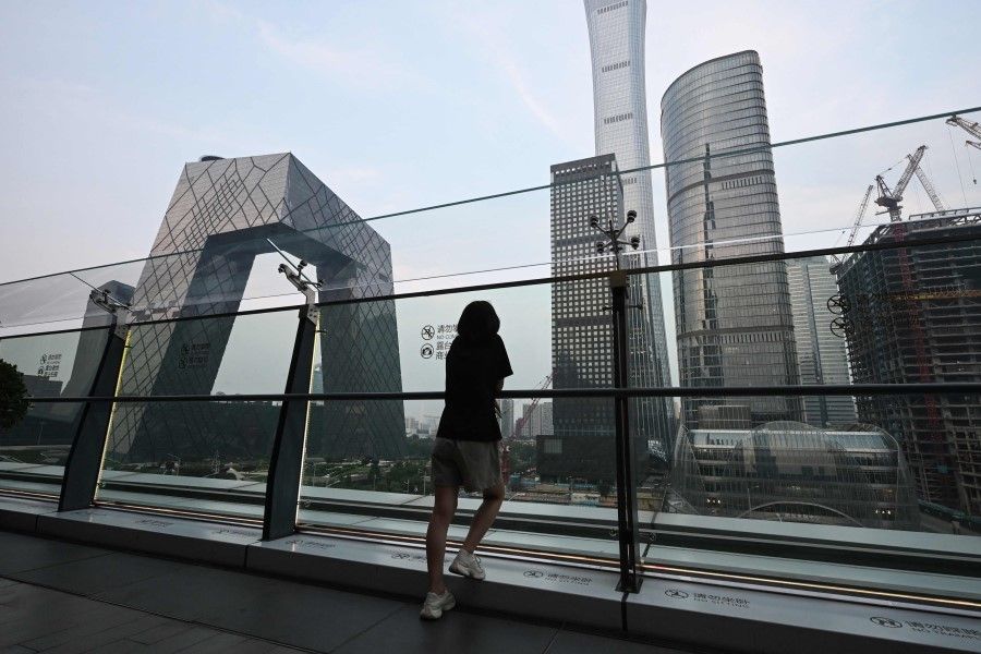 A woman looks at buildings on the the skyline from a viewing platform in a mall in Beijing’s central business district on 11 July 2024. (Greg Baker/AFP)