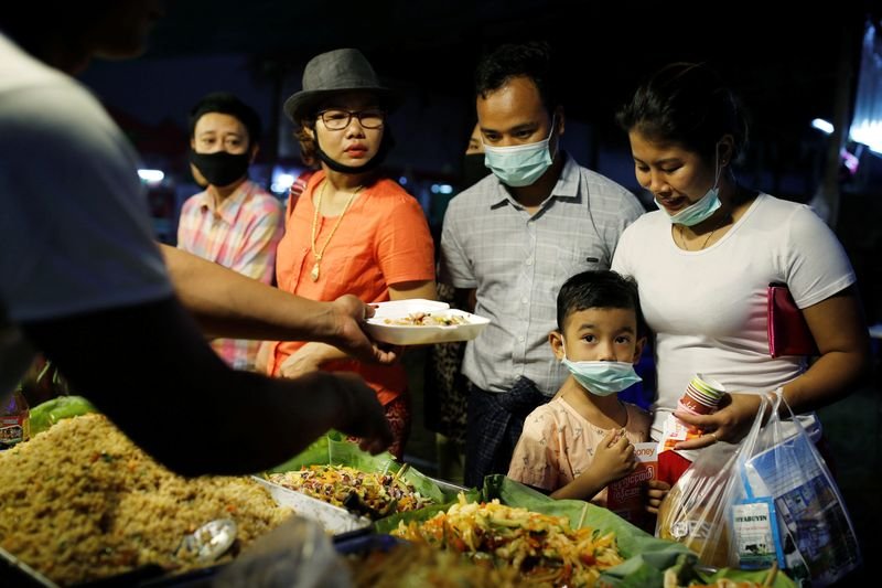 © Reuters. FILE PHOTO: A family wearing protective masks purchases food at a market in Yangon, Myanmar, February 3, 2020. REUTERS/Ann Wang/File Photo