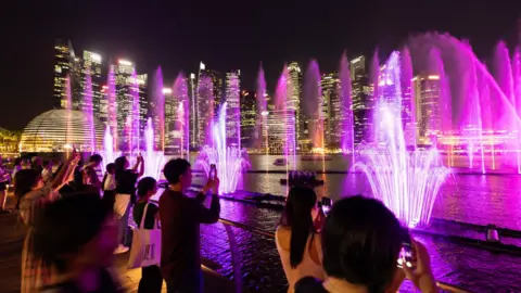 EPA Spectators take photos of a pink water light show at Singapore's Marina Bay