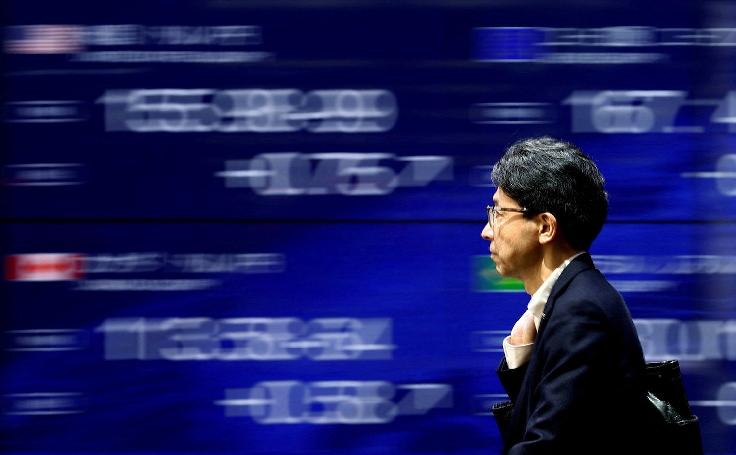 A man walks past a screen displaying the yen’s exchange rates against the U.S. dollar and other currencies in Tokyo, Japan, May 2, 2024. REUTERS/Issei Kato/File Photo