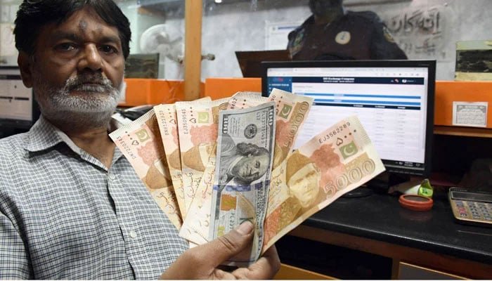 The representational image shows a foreign currency dealer posing with US dollars at a shop in Karachi on March 2, 2023. — Online