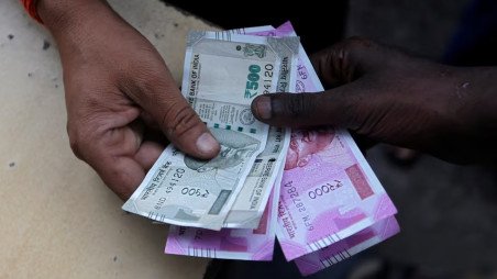 A customer hands Indian currency notes to an attendant at a fuel station in Mumbai, India, August 13, 2018. Photo: REUTERS/Francis Mascarenhas/ File Photo